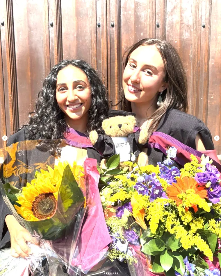 Two graduates celebrating with flowers after their degree ceremony